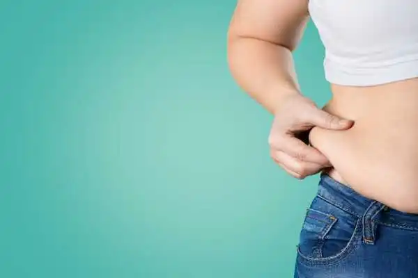 Image of woman pinching her love handles to show weight gain Great Missenden