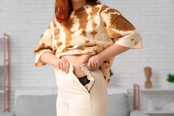 Image of woman trying to do her trousers up after pregnancy weight gain Great Missenden